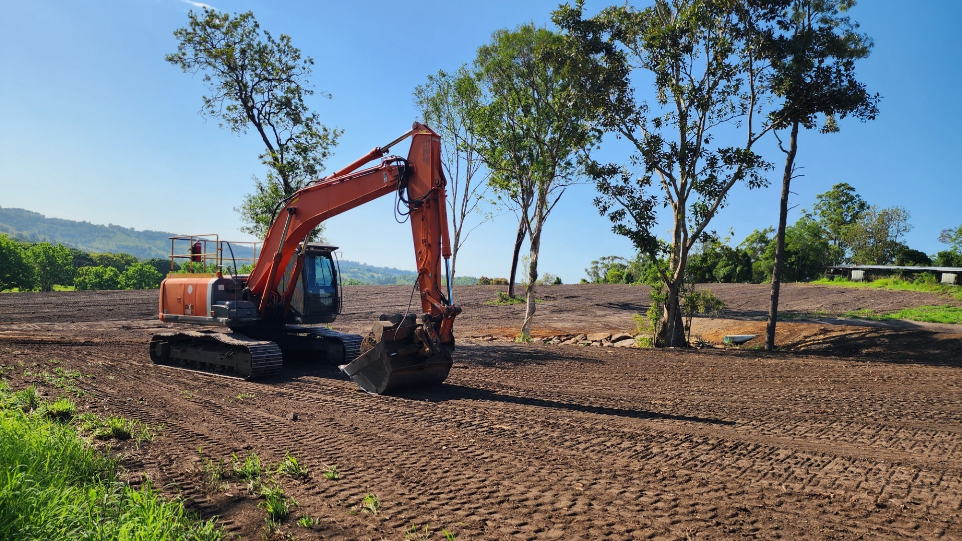 Orange excavator working on a prepared rural field