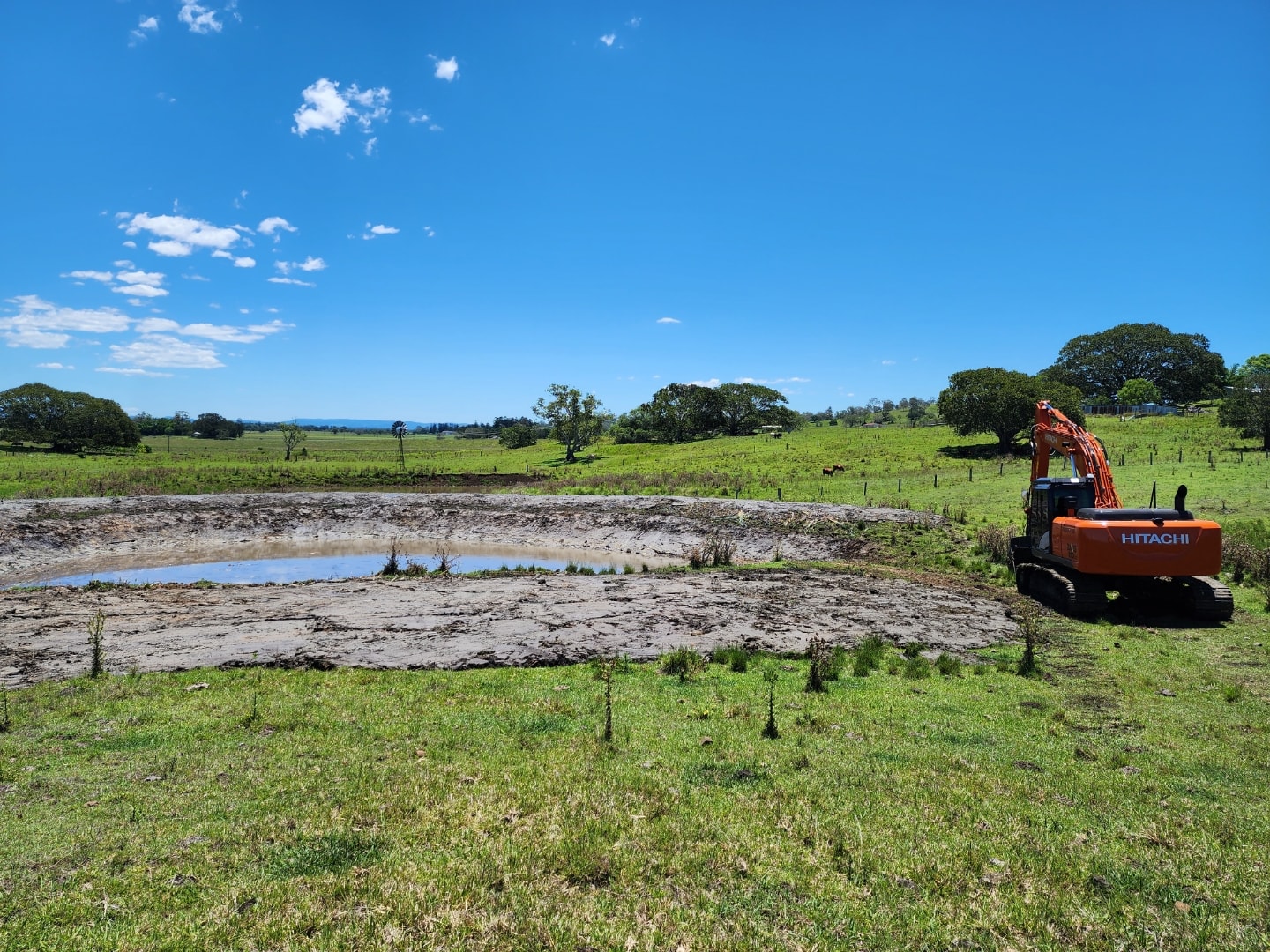 Hitachi excavator beside a rural dam