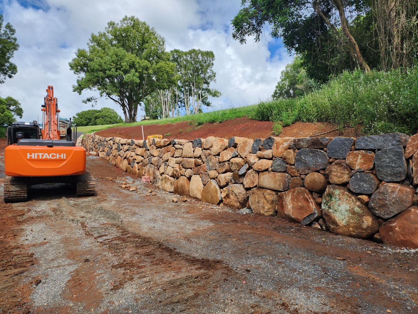 Excavator beside a newly built stone retaining wall